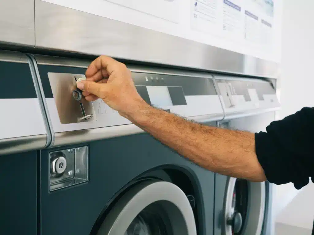 Hand-putting-quarter-in-laundry-machine
