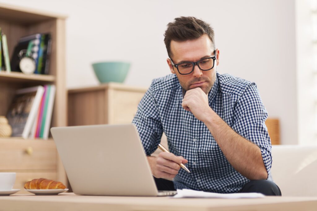 Man looking thoughtful with laptop open
