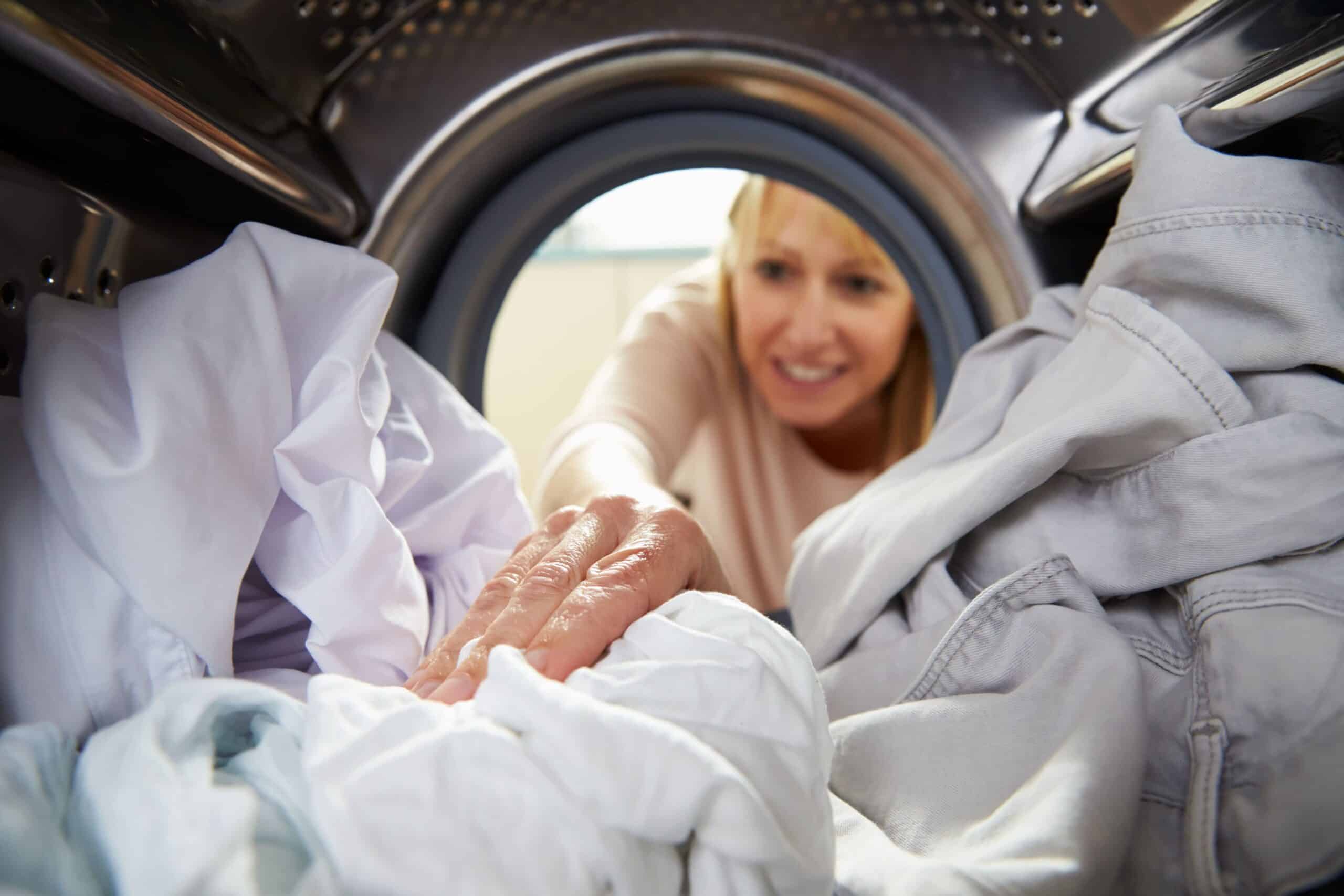 Woman adding clothes to washing machine, view from inside washer